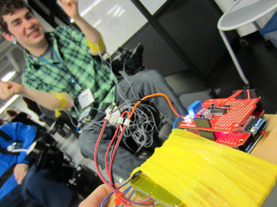 Photo of DO-IT Ambassador Sean Marihugh controls an electronic car at the Sensorimotor Neural Engineering pizza party.