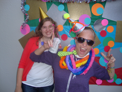 Photo of DO-IT Interns Erika and Kaylie are dressed up in party hats and crafts while posing in front of a polka dot background