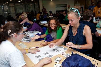 Photo of Phase II DO-IT Scholars Alicia and Aaliyah do an activity with cards with Intern Kaylie during the video games workshop during Summer Study 2013