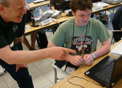 A mentor works with a high school student in a computer lab.