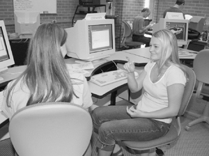 Two DO-IT Ambassadors use sign language to talk to each other in a computer lab. Photo of Two DO-IT Ambassadors using sign language to talk to each other in a computer lab.
