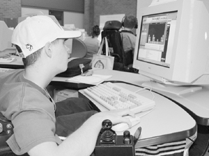 Student in wheelchair uses a mouse to work on a computer program about blocks. Photo of Student in wheelchair using a mouse to work on a computer program about blocks.