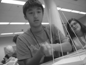 DO-IT Scholar working on a science project involving wooden sticks Image of a DO-IT Scholar working on a science project involving wooden sticks