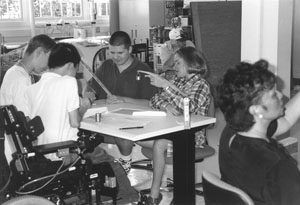 Image of four scholars gathering around a table to work on a project.