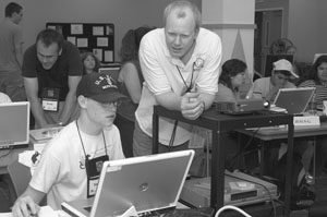 Photo of Members of the program staff help DO-IT Scholars who are working on projects on their laptops.