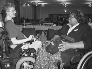 DO-IT Scholar interacting with another person. Image of a DO-IT Scholar in a wheelchair having a woman in a wheelchair.