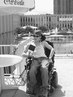 Image of a DO-IT Scholar wearing sunglasses poses in her wheelchair on a patio.