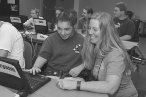 Photo of Lisa Stewart helps a Scholar with a project on a laptop.