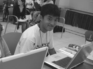 Photo of DO-IT Scholar looks up from his laptop to smile at the camera.