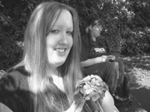 Photo of DO-IT Scholar holds a flower as she smiles for the camera.