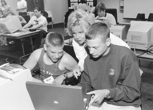 Sheryl Burgstahler works with two Scholars at a lap top computer. Photo of Sheryl Burgstahler works with two Scholars at a lap top computer.