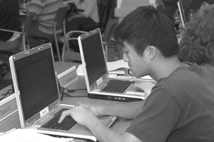 DO-IT Scholar types on his lap top in the DO-IT computer lab. Photo of DO-IT Scholar typing on his lap top in the DO-IT computer lab.