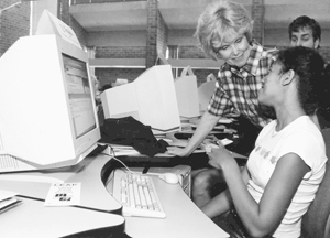 Photo of DO-IT Scholar consulting DO-IT director Sheryl Burgstahler on a computer issue while in the computer lab with other DO-IT Scholars.