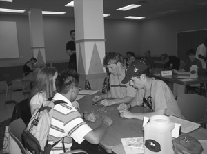 Photo of Four students working in a group to solve a problem sit around a table in a classroom.