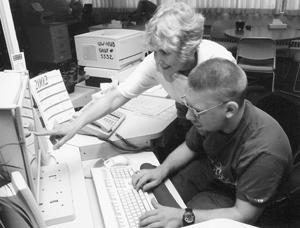 Photo of Sheryl Burgstahler points to something on a computer screen for DO-IT Ambassador.