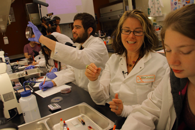 Picture of two students working with a science lab instructor to conduct a science experiment.