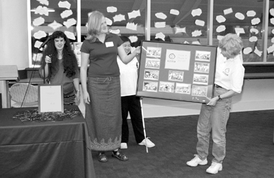 Picture of '93 Scholars Anna, Katie, and Nhi present Director Sheryl with a photo montage representing each Scholar class.