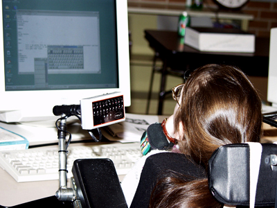 Photo of a student in a wheelchair using adaptive techonlogy to control a laptop.