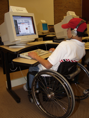 Photo of student in a wheelchair working at a computer workstation.