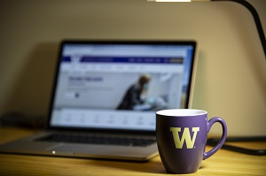 A University of Washington-branded mug sits in front of an open laptop