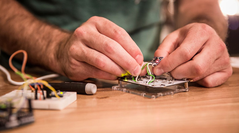 Closeup of hands working on circuit board