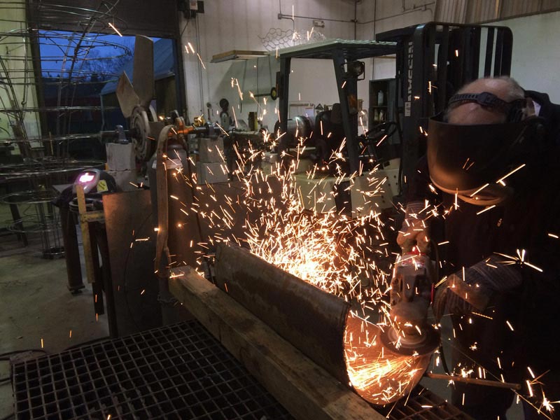 Artist using angle grinder on metal piece